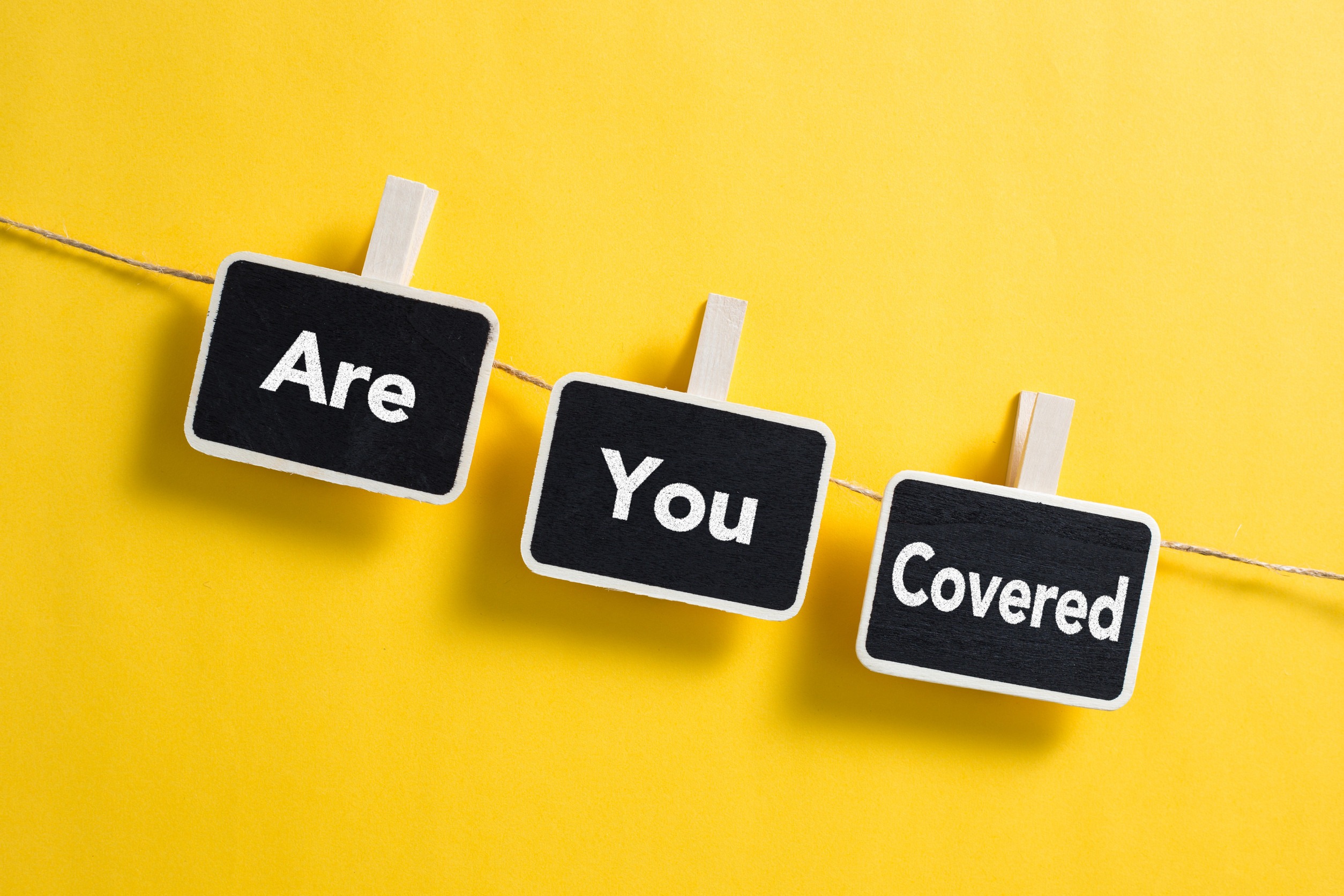 Three small blackboards with white borders hang on a string against a yellow background, each displaying 