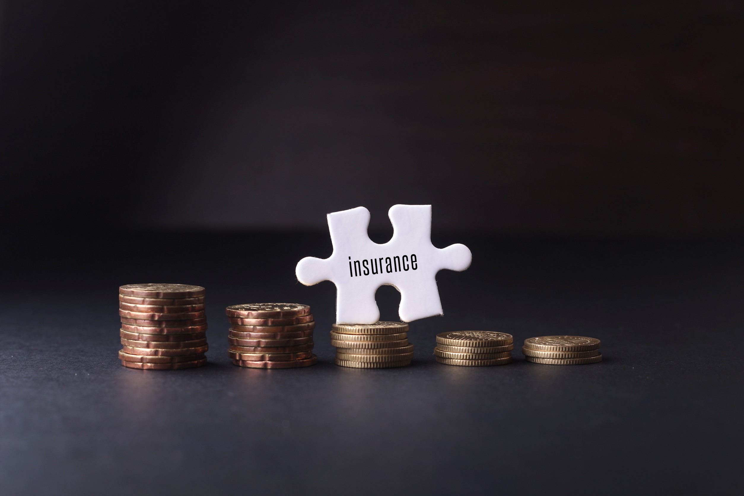 Four stacks of coins sit on a dark surface, with a white puzzle piece labeled 