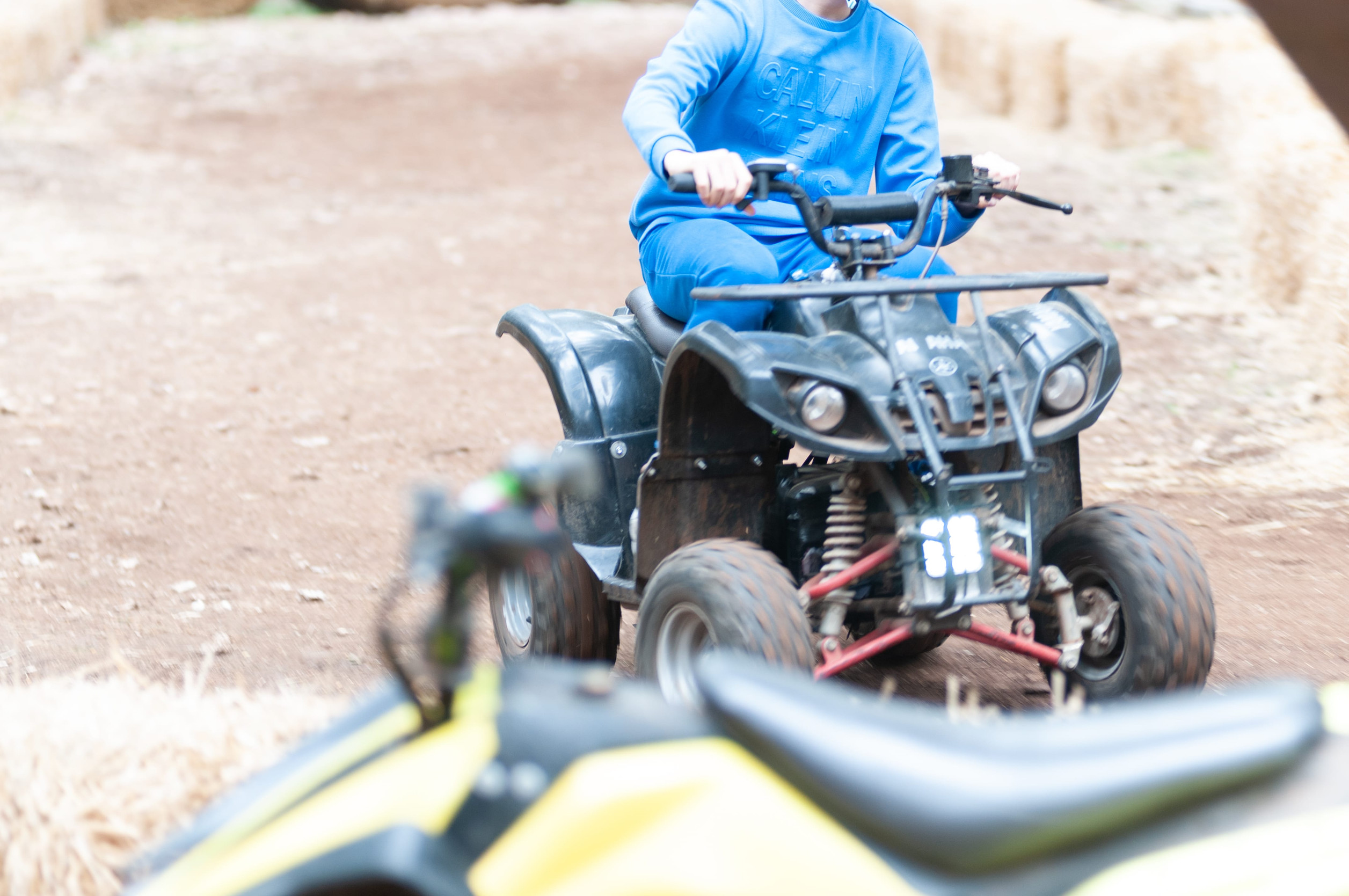 A person in a blue sweatshirt rides a black ATV on a dirt track, highlighting the importance of Minnesota ATV insurance.